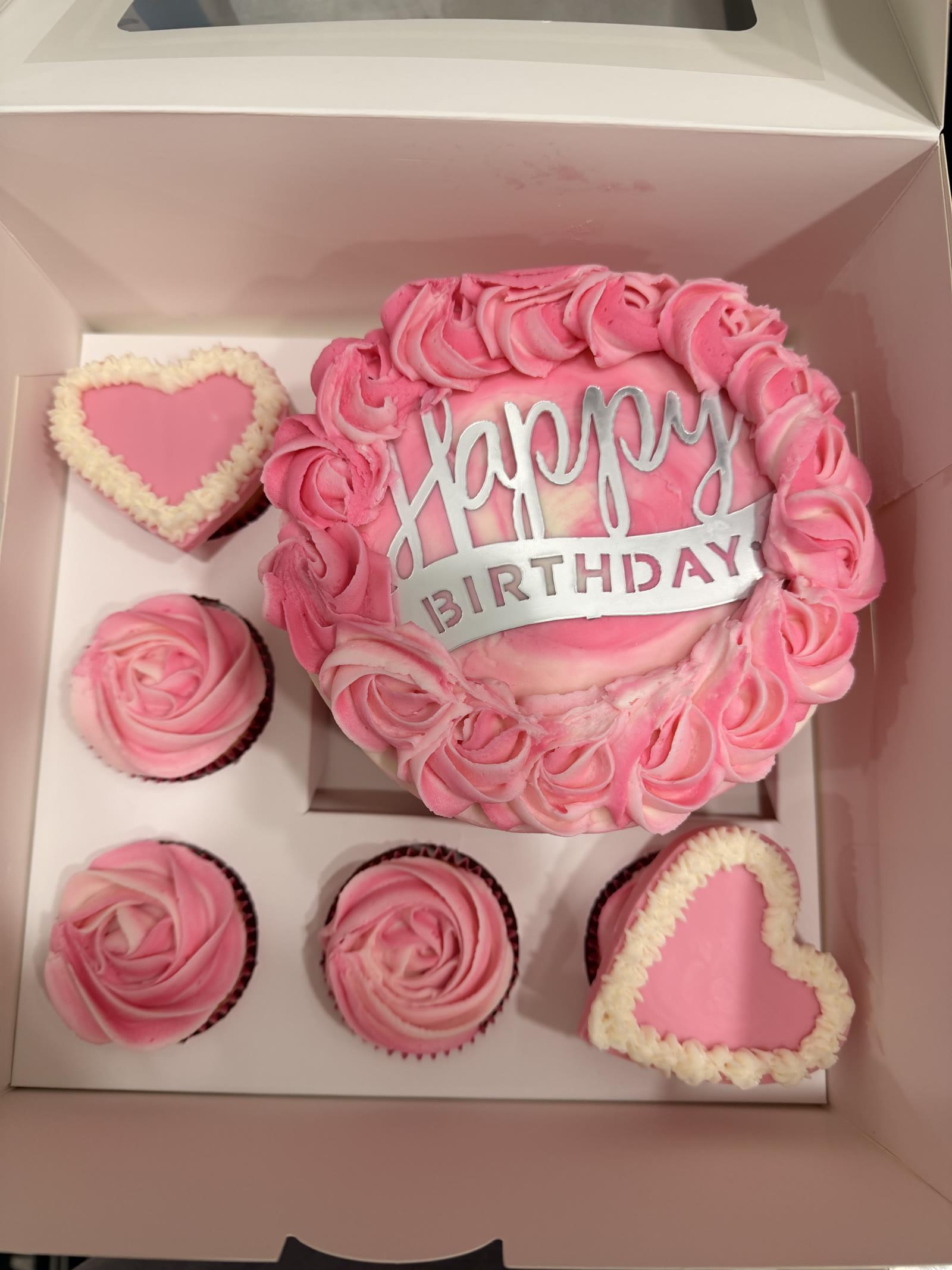 Pink birthday bento box with a rosette cake, heart-shaped mini cakes, and swirled cupcakes