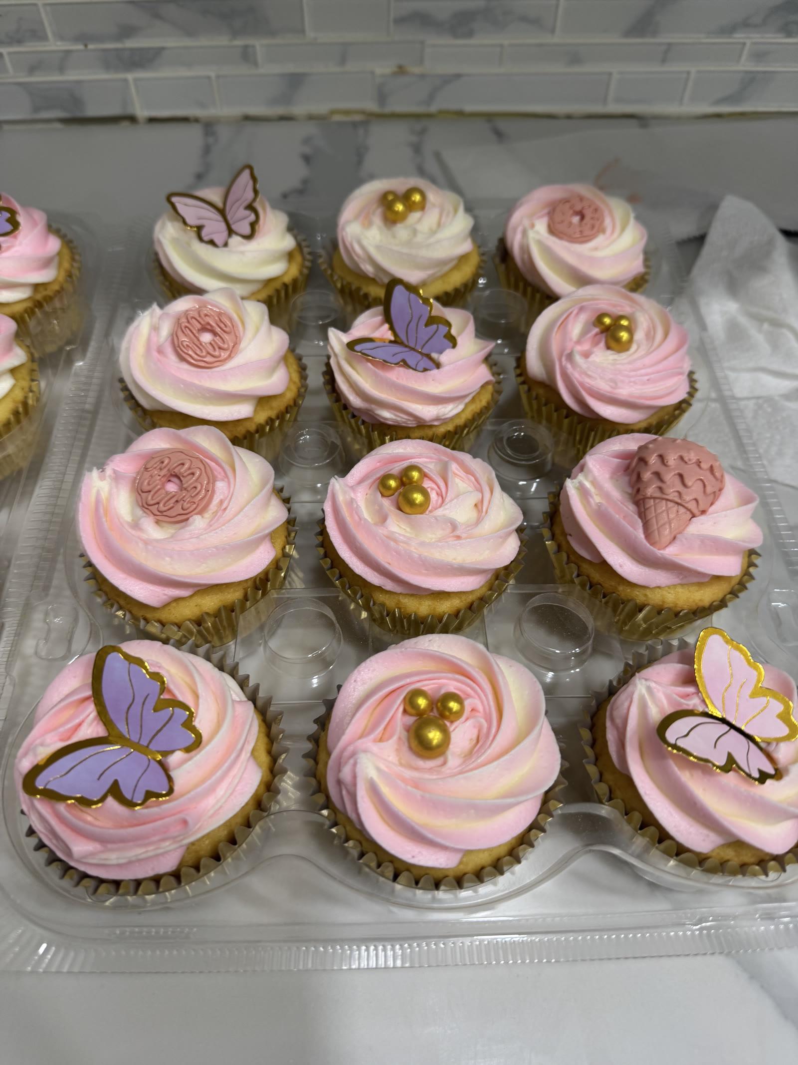 Pink and white swirled cupcakes decorated with purple and pink butterflies and gold pearls
