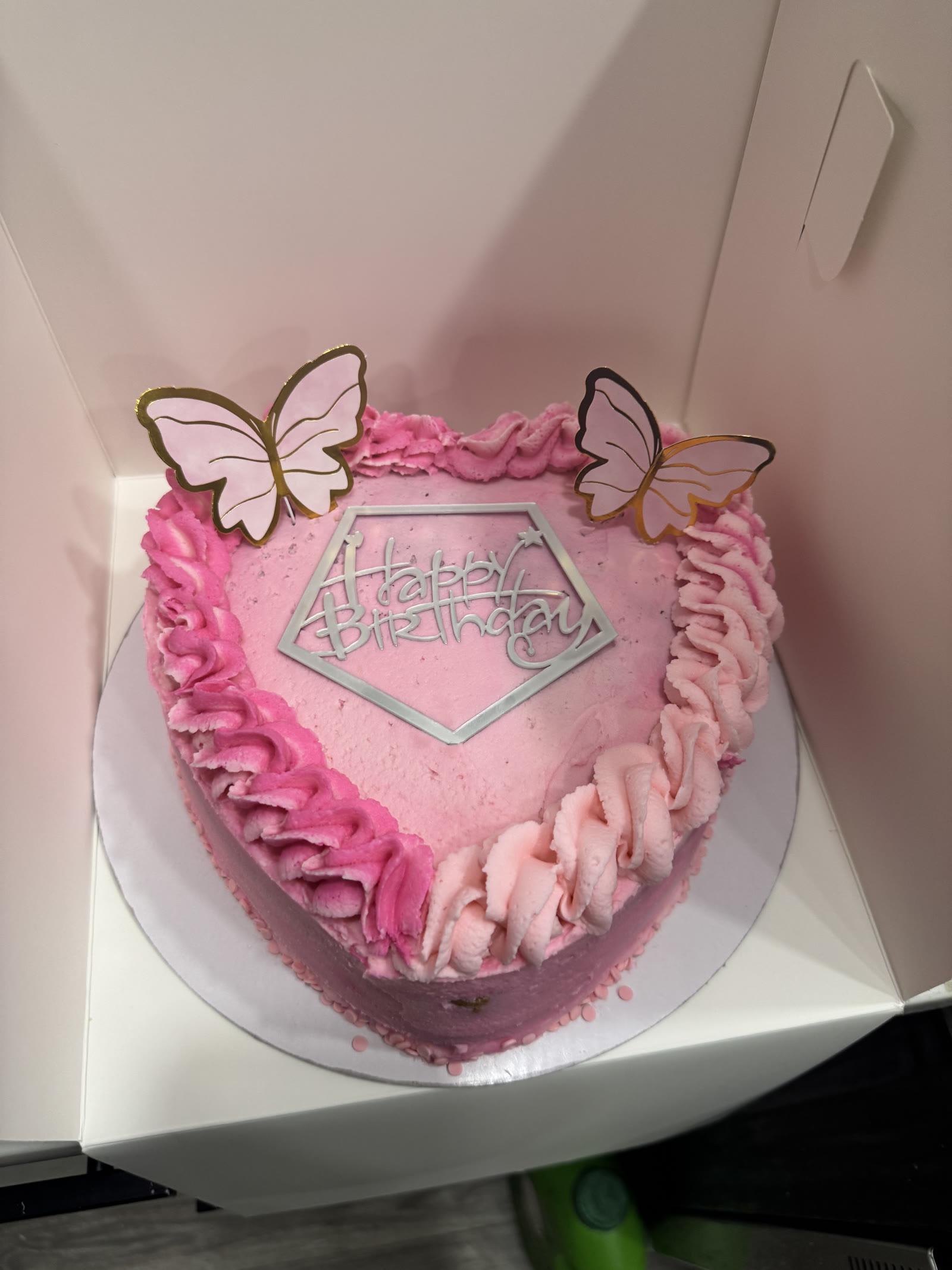 Heart-shaped pink ombre birthday cake with ruffled piping and butterfly toppers