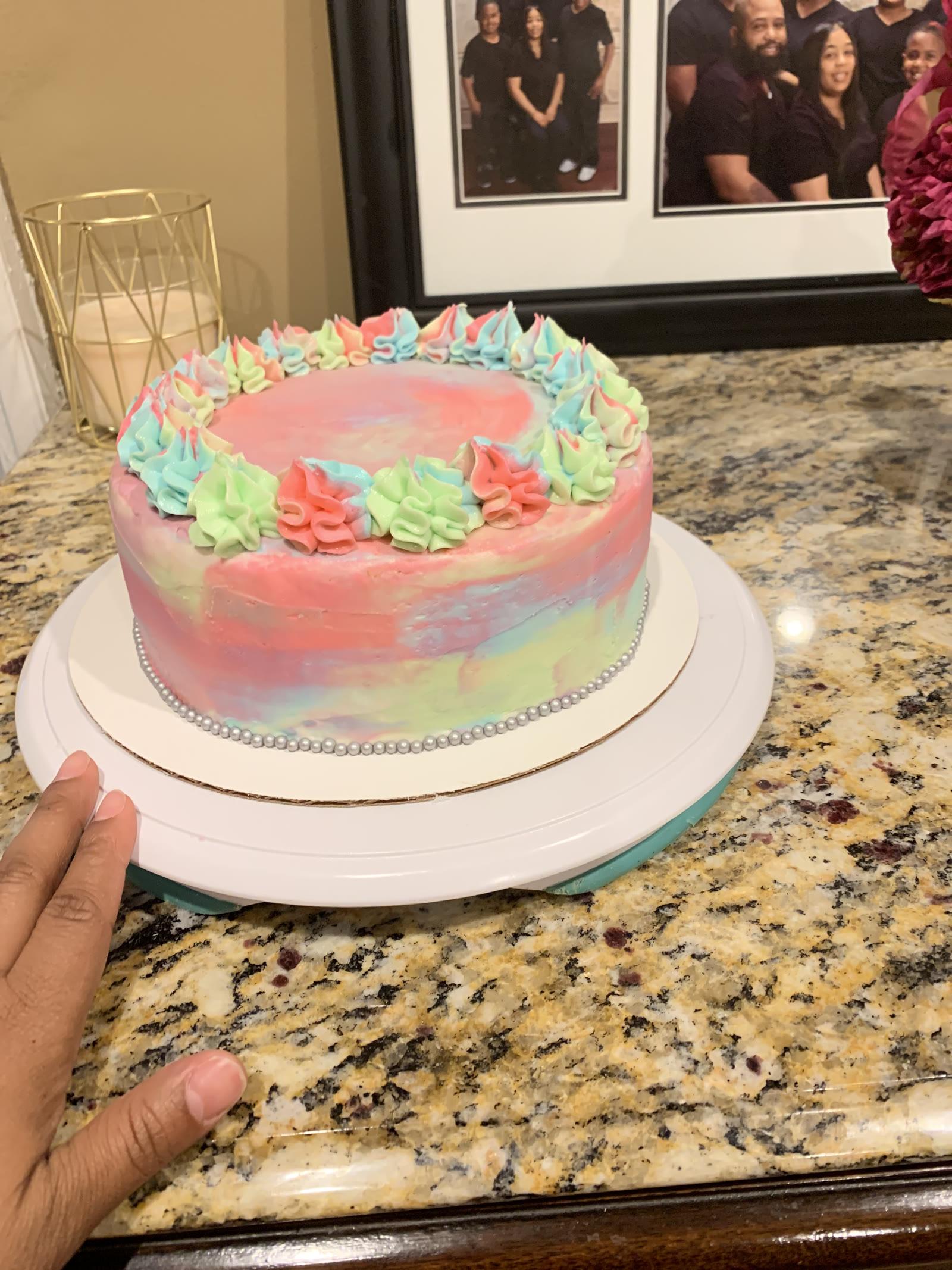 Pastel watercolor cake in pink, blue, and green with star piping and a pearl border