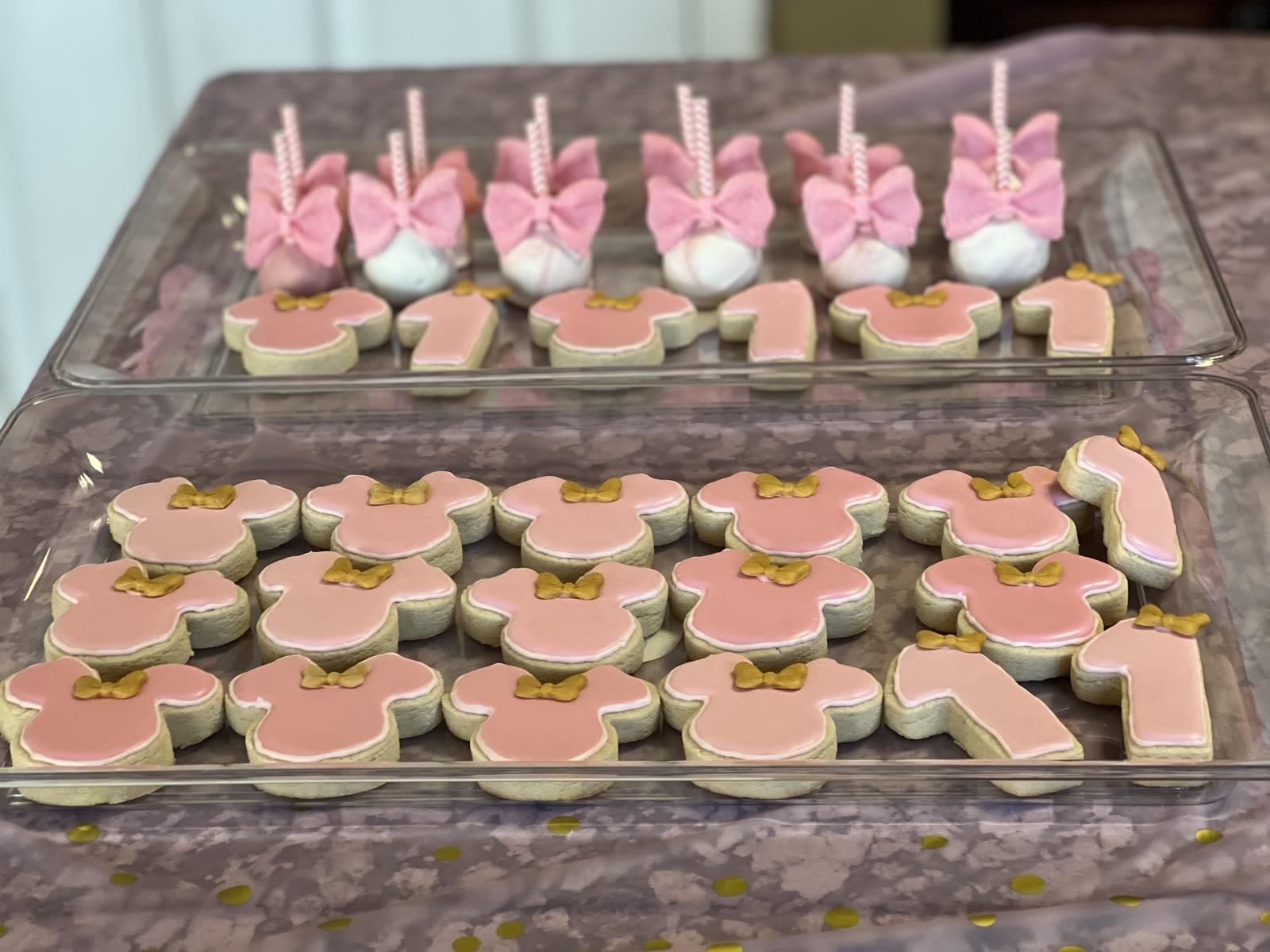 Hand-decorated sugar cookies and cake pops arranged on party trays
